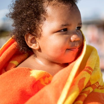 baby wrapped in orange and yellow beach towel