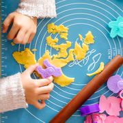 young girl using rolling pin and cookie cutters