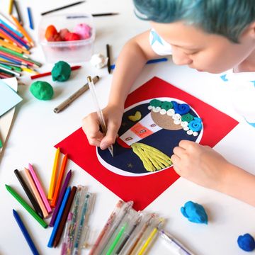 kid with blue hair drawing stars on cut paper and clay lighthouse craft