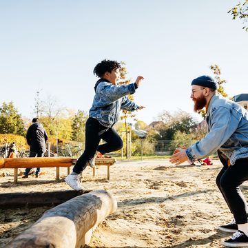 kid in jean jacket jumping to dad on playground