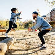 kid in jean jacket jumping to dad on playground