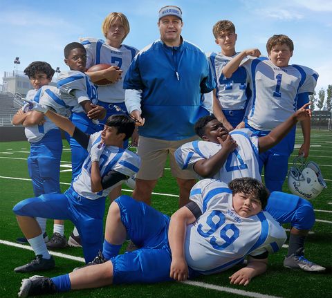 kevin james poses with a football team for home team, a good housekeeping pick for best kids movies 2022