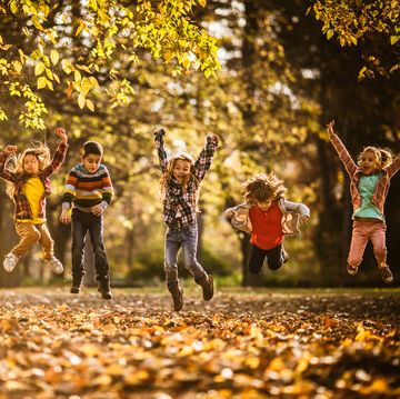 large group of playful kids having fun while jumping during autumn day in nature copy space