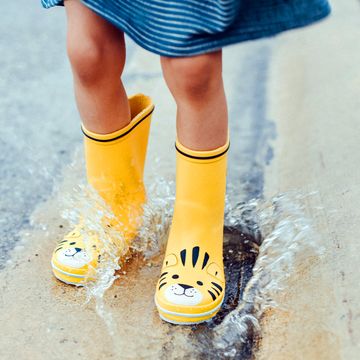 kid jumping in puddle wearing yellow rain boots