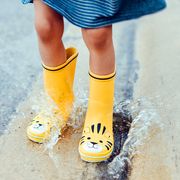 kid jumping in puddle wearing yellow rain boots