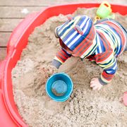 kid playing in sandbox with beach toys