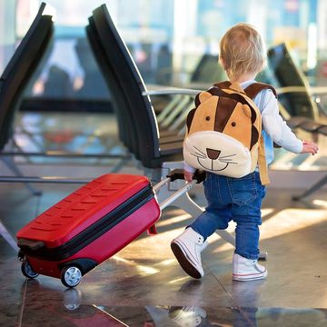 toddler with lion backpack rolling red kids suitcase in airport
