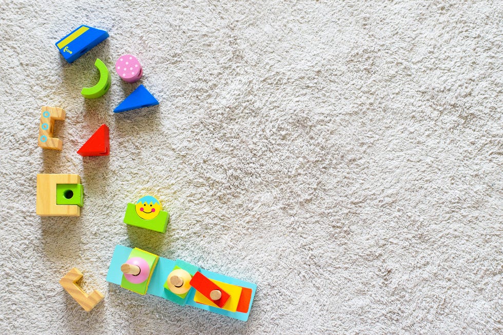 colorful wooden pyramid with geometric details on a white cotton carpet eco friendly, plastic free toys for toddler space for text
