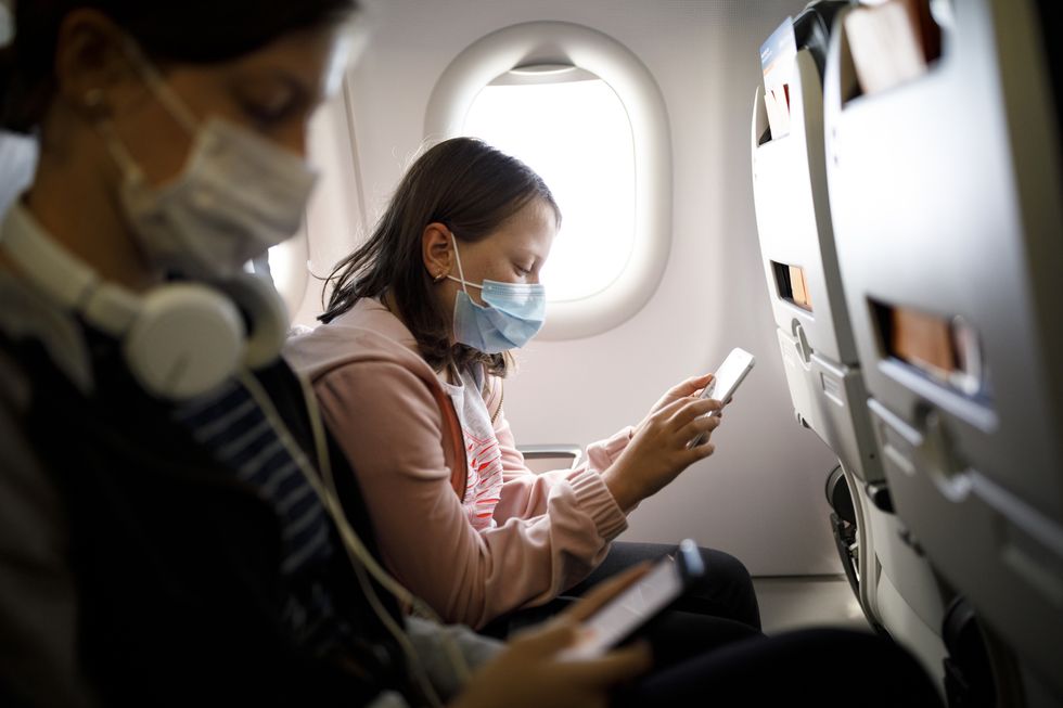 kids with face protective mask using mobile phone in airplane
