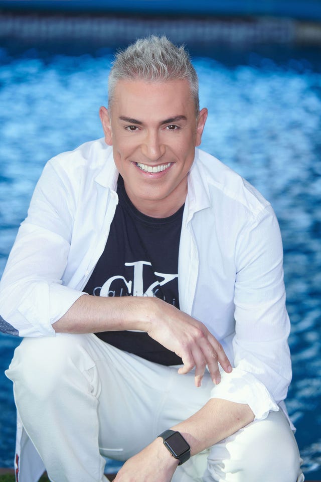 el colaborador posa con camiseta negra, camisa y pantalón blanco