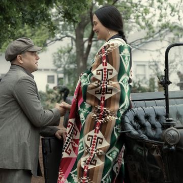 a man and woman standing next to a car with a decorated scarf