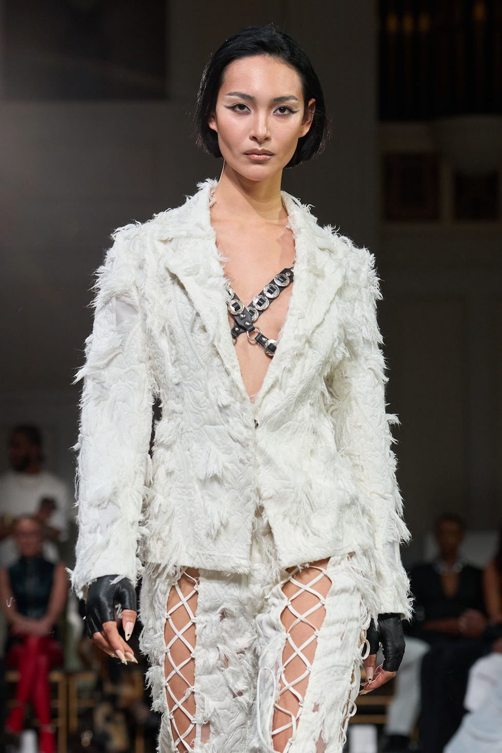 Fashion model on the runway in a textured white outfit featuring intricate details and a unique design