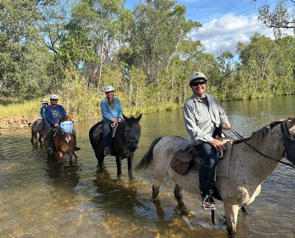 a group of people riding horses through a river