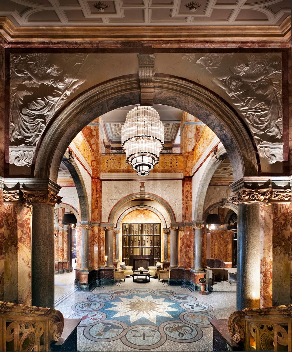 Ornate hotel lobby with pillars, tiled floor and giant chandelier