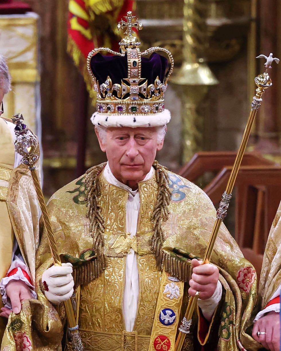 king charles holds two scepters and wears a large crown and golden robes, he looks forward