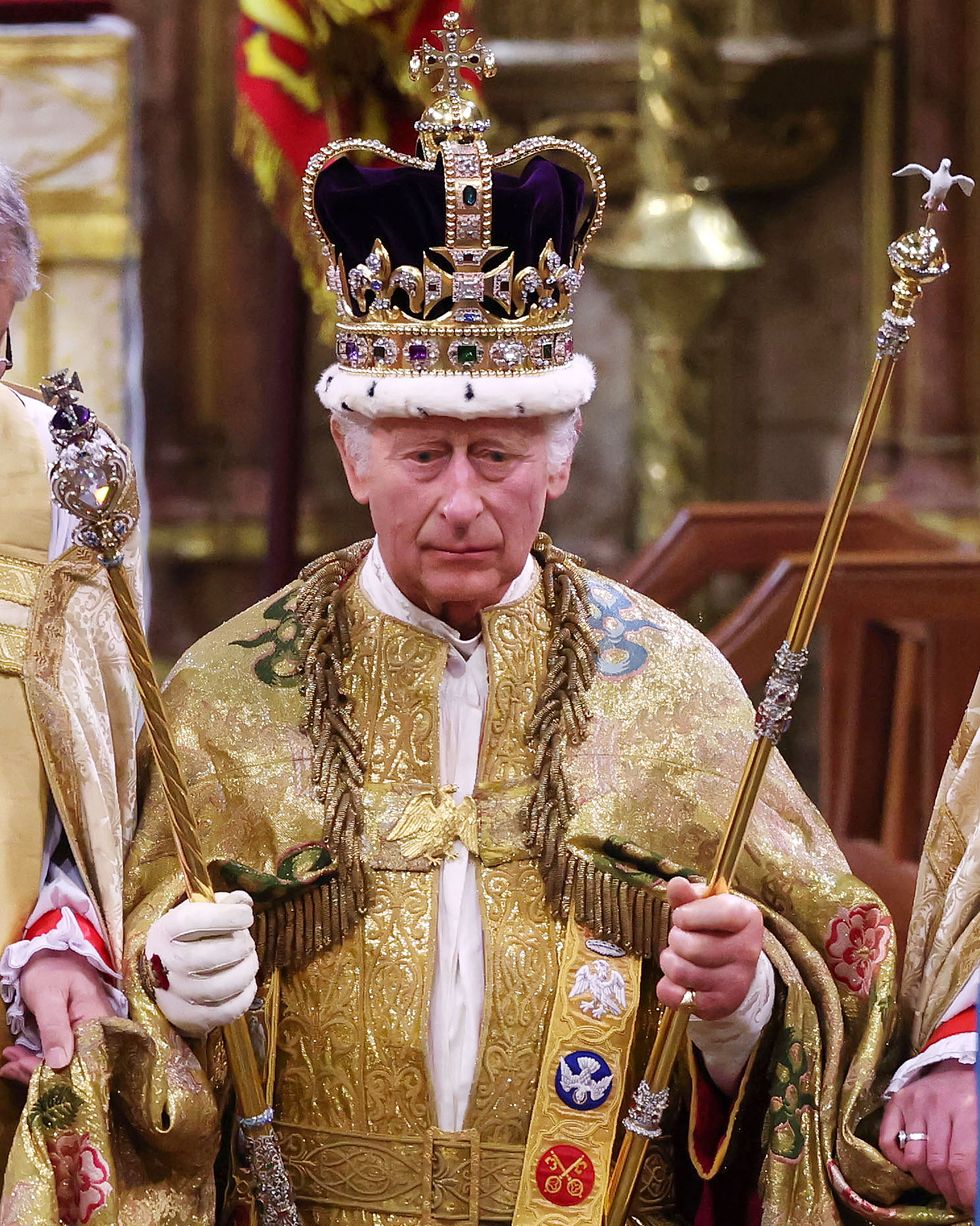 king charles holds two scepters and wears a large crown and golden robes, he looks forward