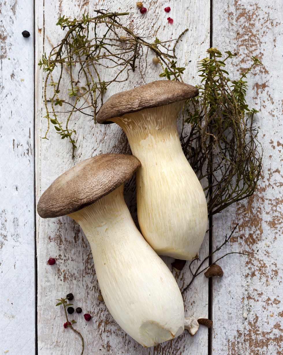 king trumpet mushrooms, thyme and peppercorns on wood
