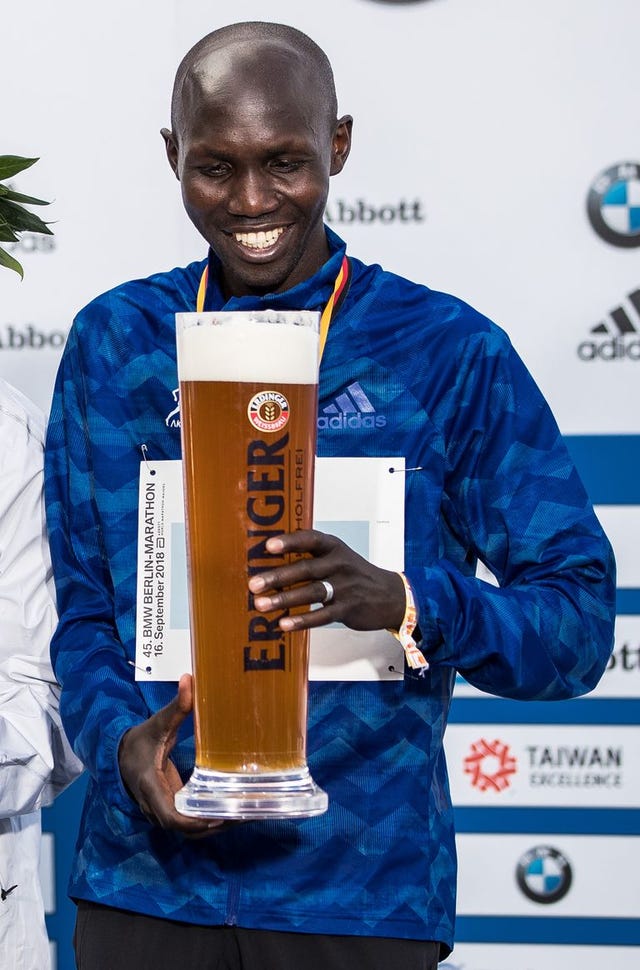 Kipsang (derecha) sostiene una cervez en el podio del maratón de Berlín del año 2018.