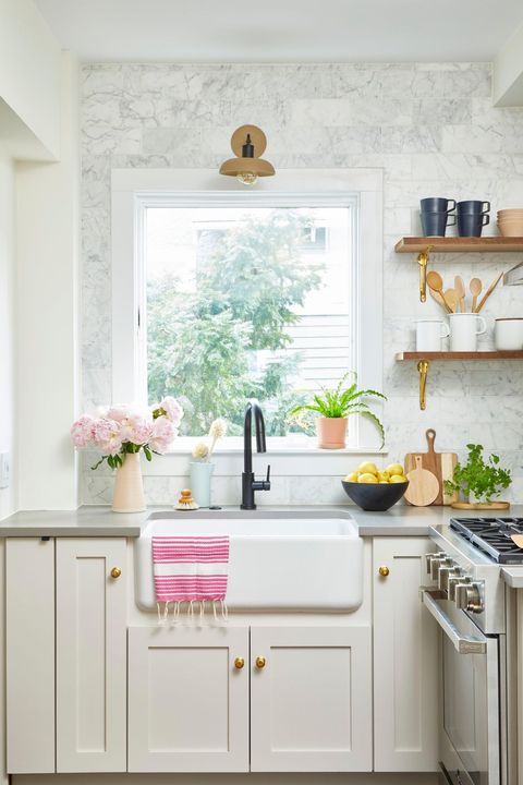 kitchen backsplash ideas neutral marble tile backsplah with white cabinets and gold accents by the sink window