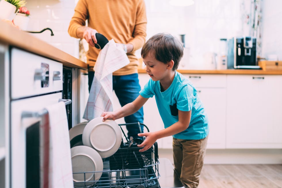 Dish washing concept. Child boy washing the dishes in the kitchen