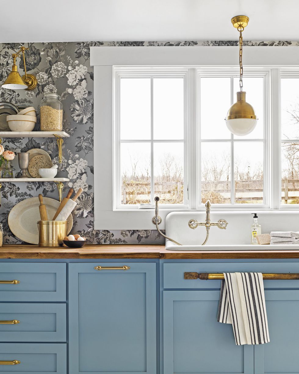 kitchen with blue painted cabinets paired with a silvery tone on tone floral wallpaper