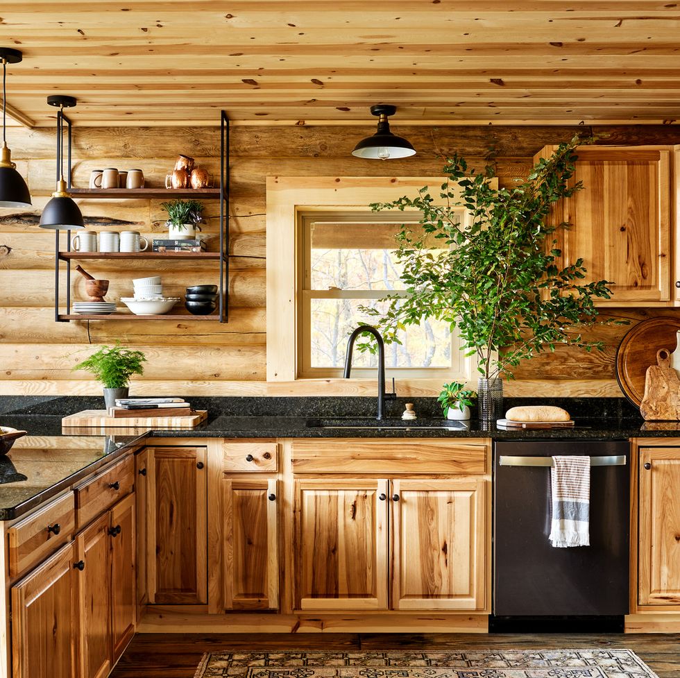 a pine wood kitchen with black appliances and countertops and lighting