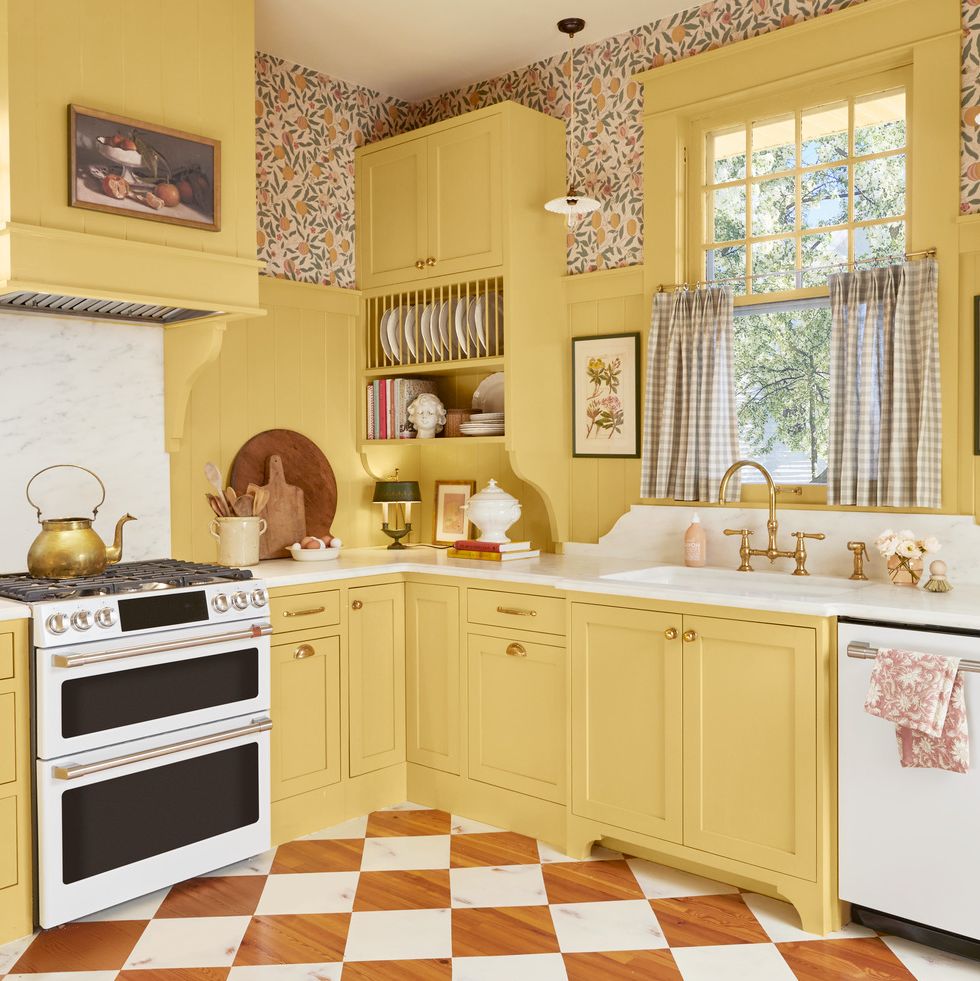 a cheery sunny yellow kitchen with gingham curtains and white marble countertops that extend into an ornately carved backsplash behind the sink