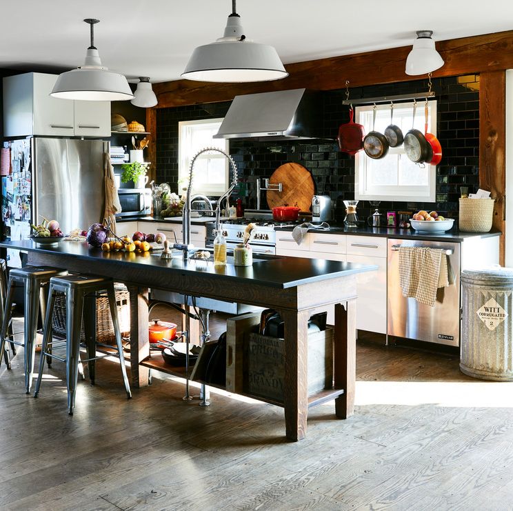 a modern farmhouse style kitchen with oversize white pendant lighting and an island with black countertops