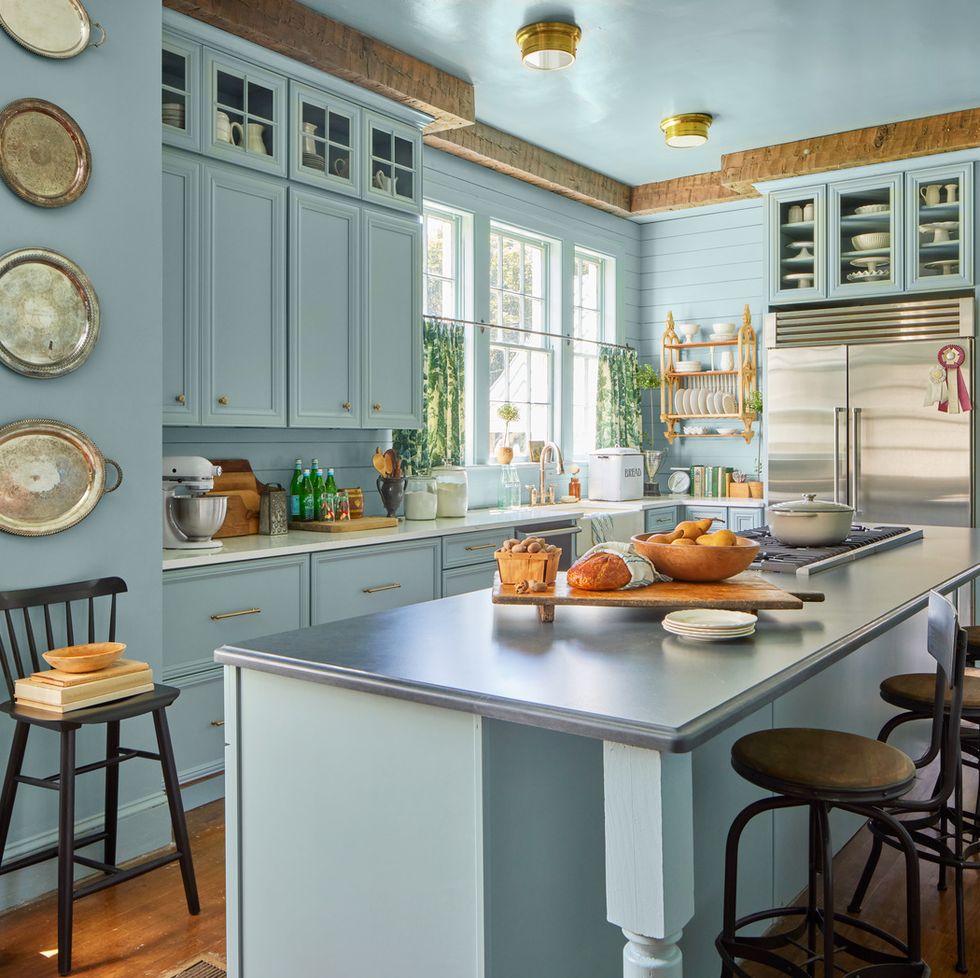 a blue kitchen with a large island that has a gray countertop
