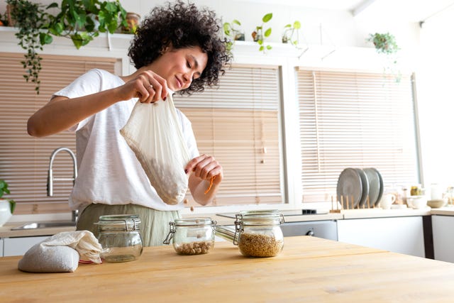 young multiracial woman putting away chickpeas bought in bulk into glass containers. copy space. sustainable lifestyle concept.