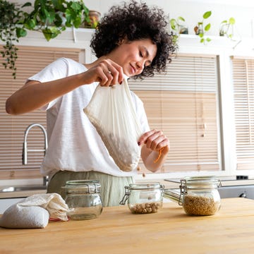 Young multiracial woman putting away chickpeas bought in bulk into glass containers. Copy space. young multiracial woman putting away chickpeas bought in bulk into glass containers. copy space. sustainable lifestyle concept.