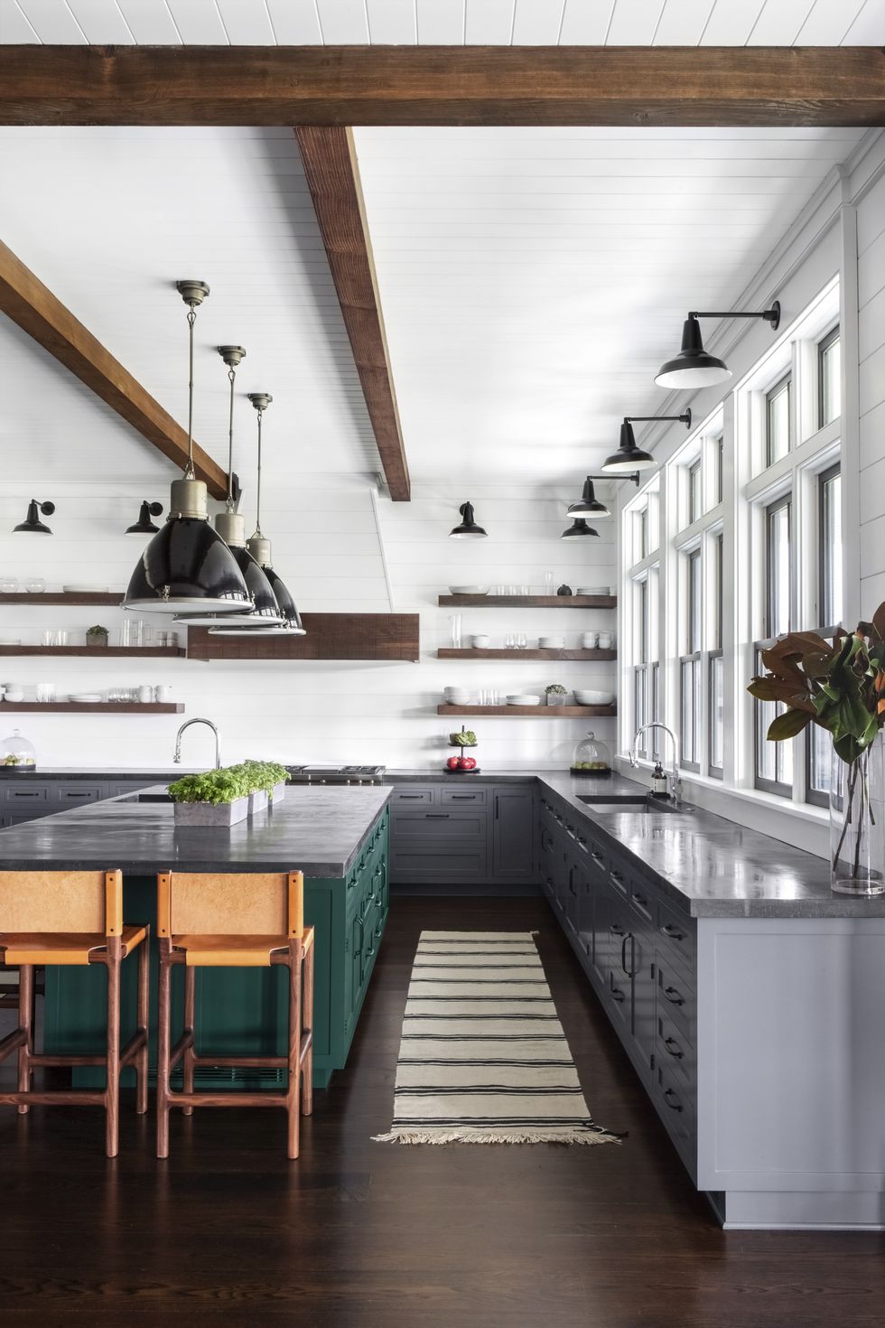 large forest green island in rustic modern kitchen with wood stools for seating, dark gray stone counters, white walls