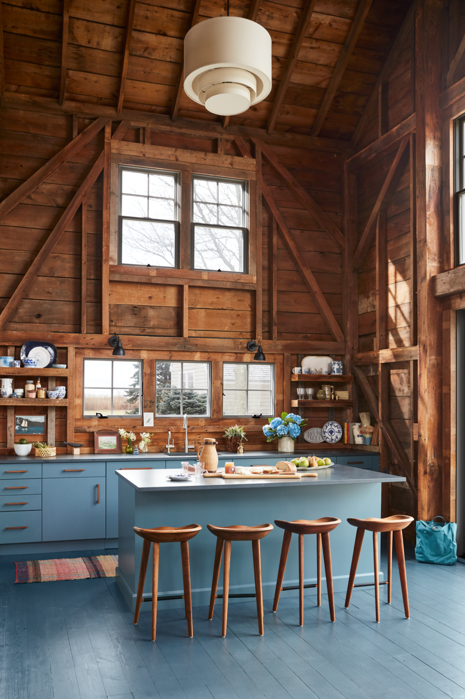 blue gray kitchen island with refrigerator drawers in rustic space with natural wood walls and vaulted ceiling