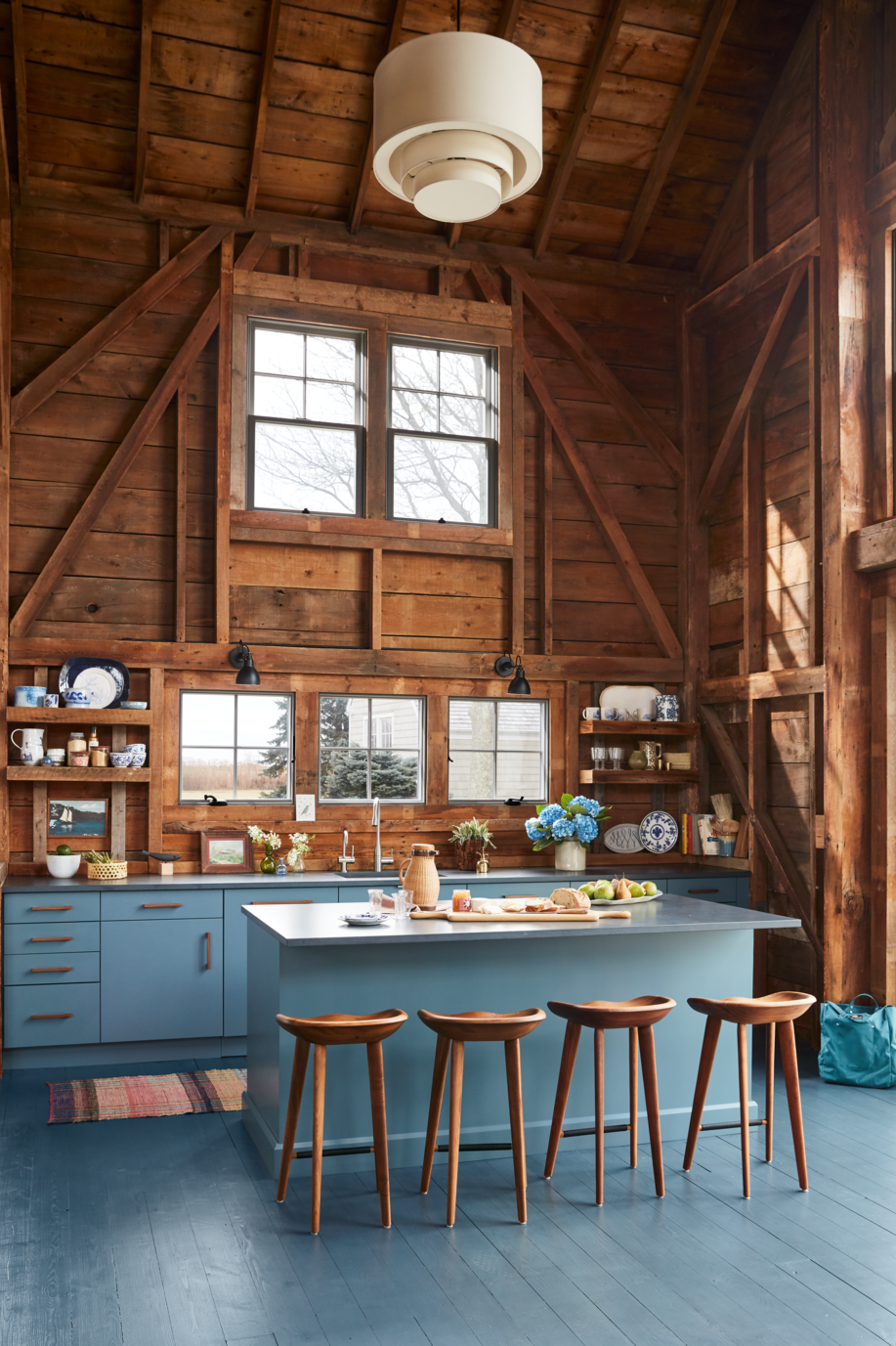blue gray kitchen island with refrigerator drawers in rustic space with natural wood walls and vaulted ceiling