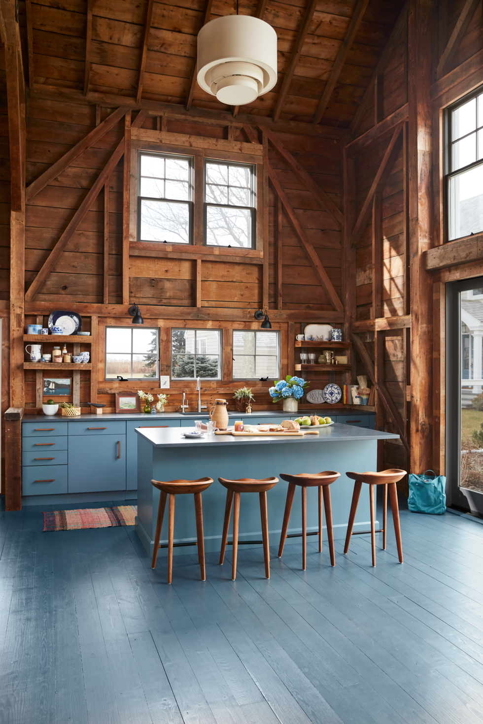 blue gray kitchen island with refrigerator drawers in rustic space with natural wood walls and vaulted ceiling