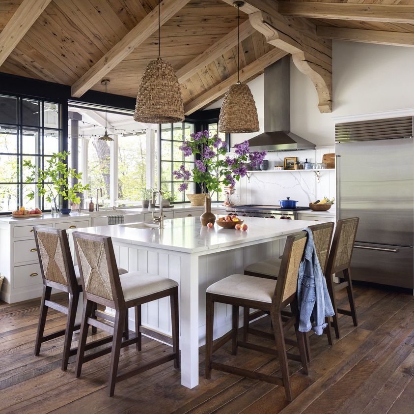 a kitchen with a large white island and straw looking barstools and light fixtures like baskets