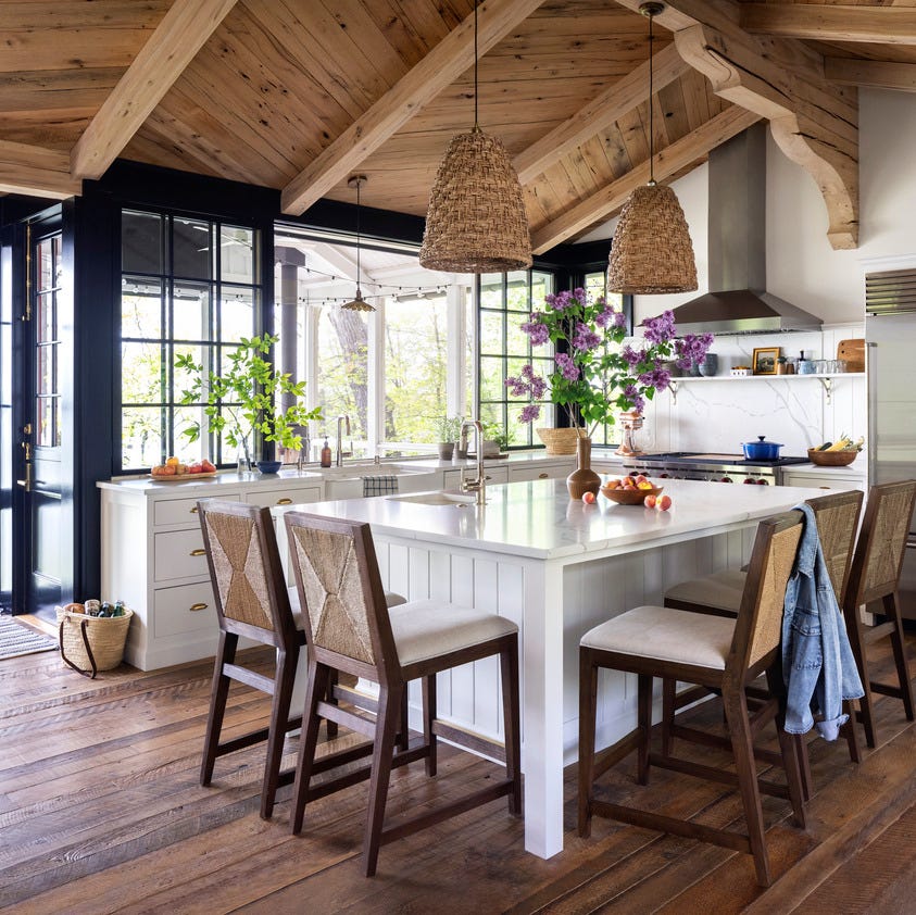 a kitchen with a large white island and straw looking barstools and light fixtures like baskets