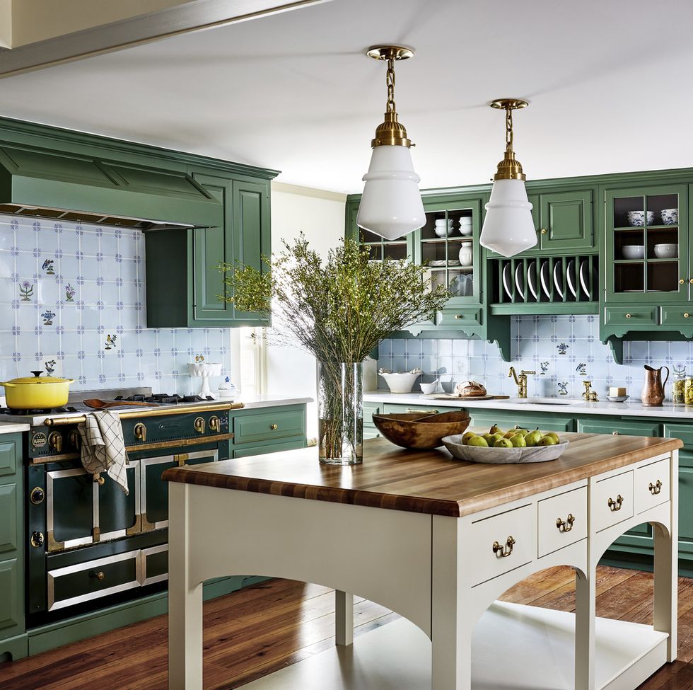 a kitchen with green cabinets and a black stove and a butcher block topped island