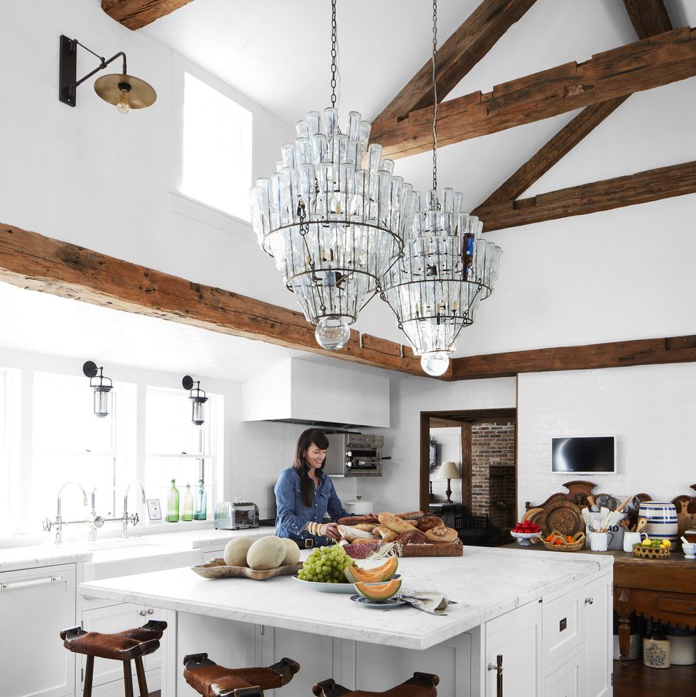 a while kitchen with wood ceiling beam and two massive crystal chandeliers over the island