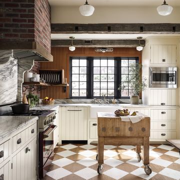 rustic kitchen with cream cabinetry and oak flooring painted in a cream and natural wood checkerboard pattern set on the diagonal