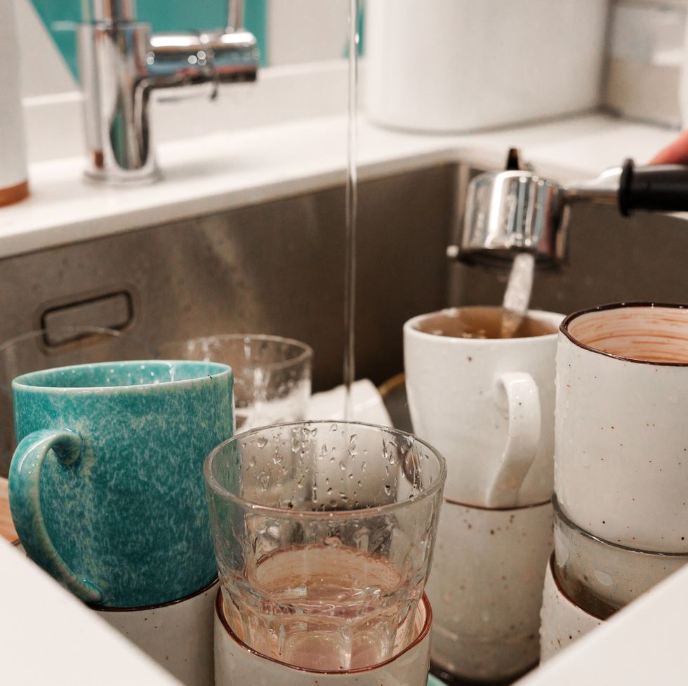 a kitchen sink with a lot of dirty dishes, mugs and plates.