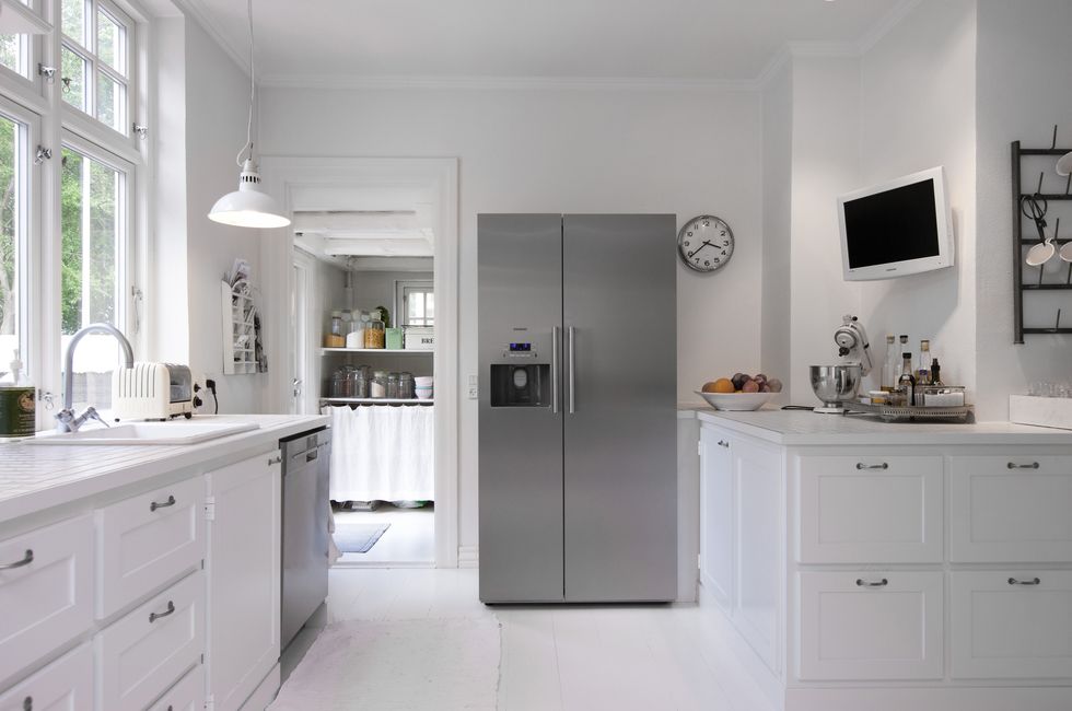 White kitchen with silver upright fridge in Hanne Davidsen home renovation, Silkesborg, Denmark.
