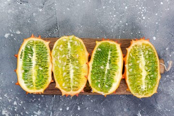 kiwano or horned melon exotic fruits cut in half on board