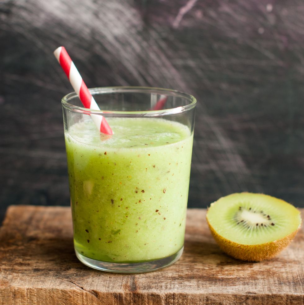 kiwi smoothie on a wooden background with paper straw