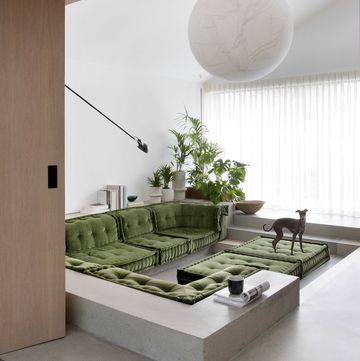 a room with a large window and a couch and a table with a plant on it