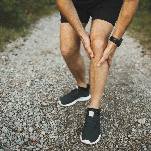 knee injury on running outdoors man holding knee by hands close up and suffering with pain sprain ligament or meniscus problem