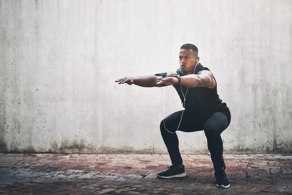 full length shot of a handsome young man listening to music while exercising outside