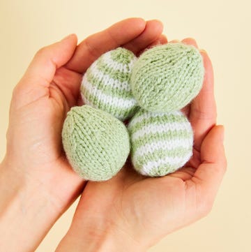 a hand holding a green and white easter eggs