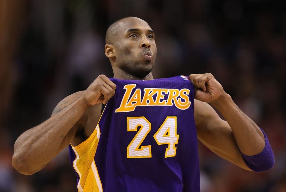 kobe bryant adjusting his purple and yellow lakers jersey during a basketball game