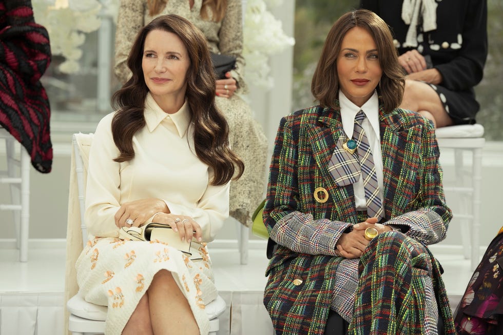 two women sitting side by side at an event each in fashionable attire